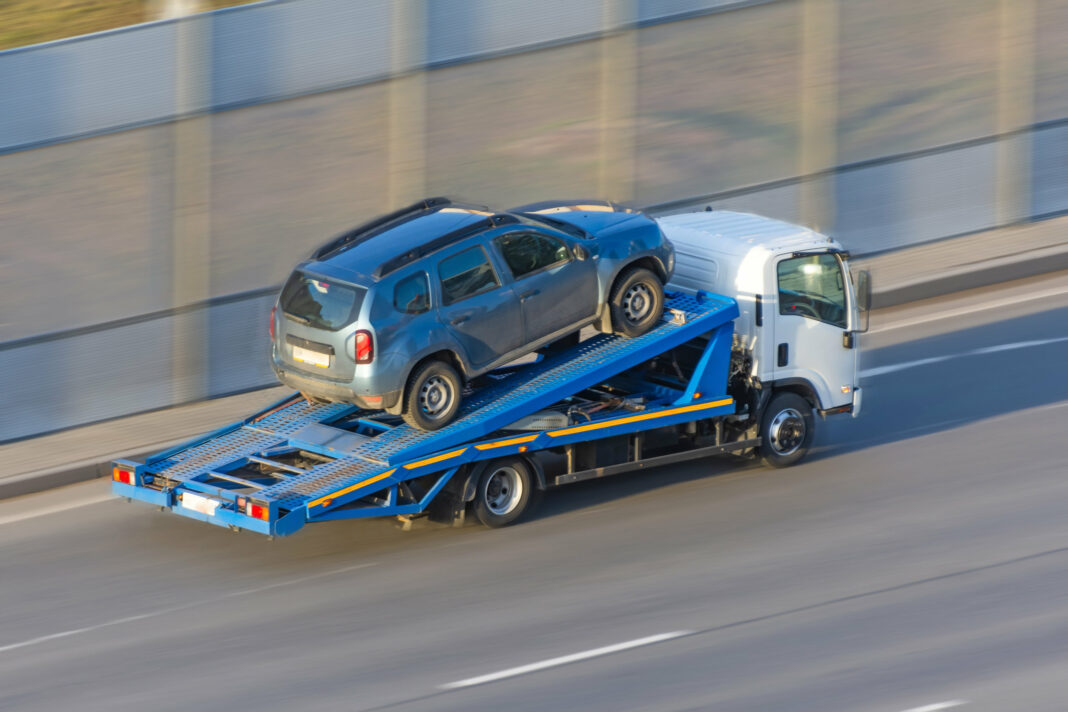 A truck carries an evacuated car on a highway, aerial view.