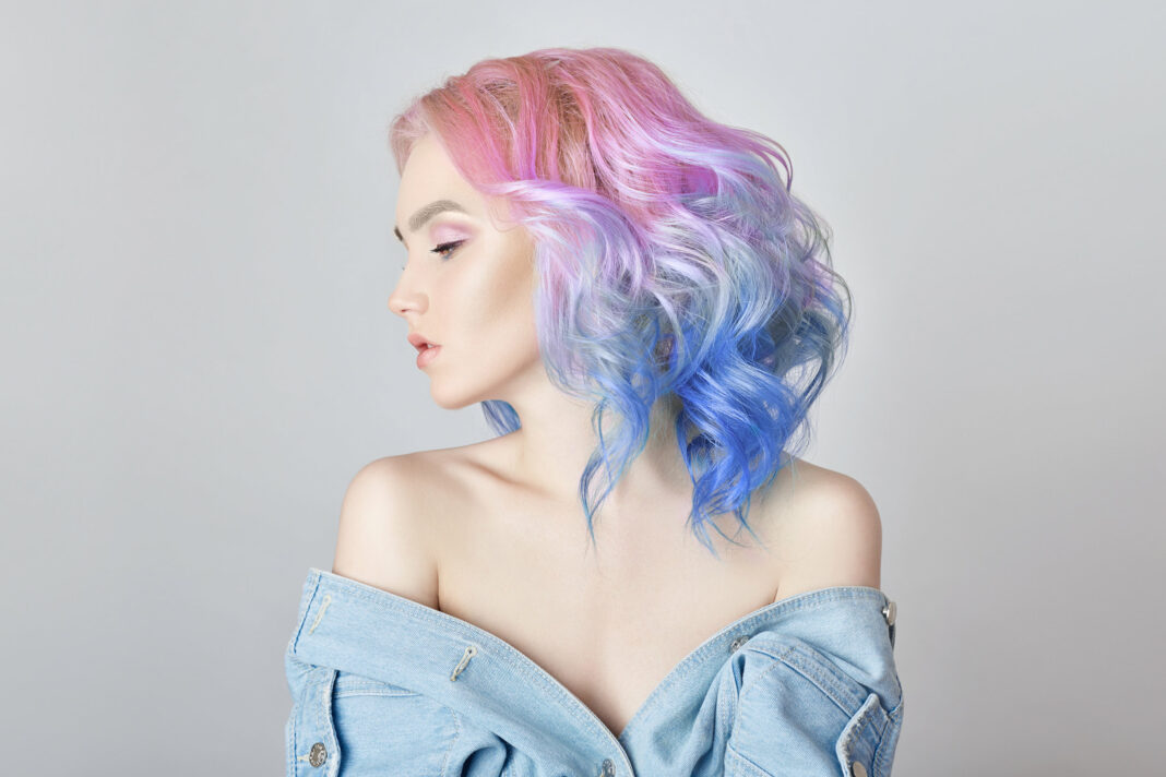 Portrait of a woman with bright colored flying hair, all shades of purple. Hair coloring, beautiful lips and makeup. Hair fluttering in the wind. Sexy girl with short hair. Professional coloring