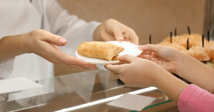 Woman,Giving,Plate,With,Tasty,Food,To,Girl,In,School