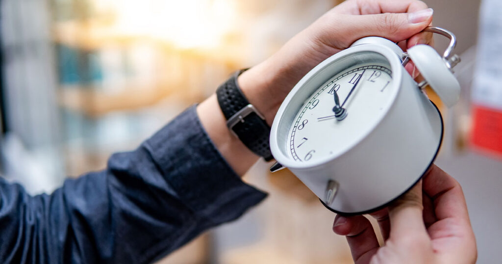 egy férfi kéz egy fehér klasszikus órát állít