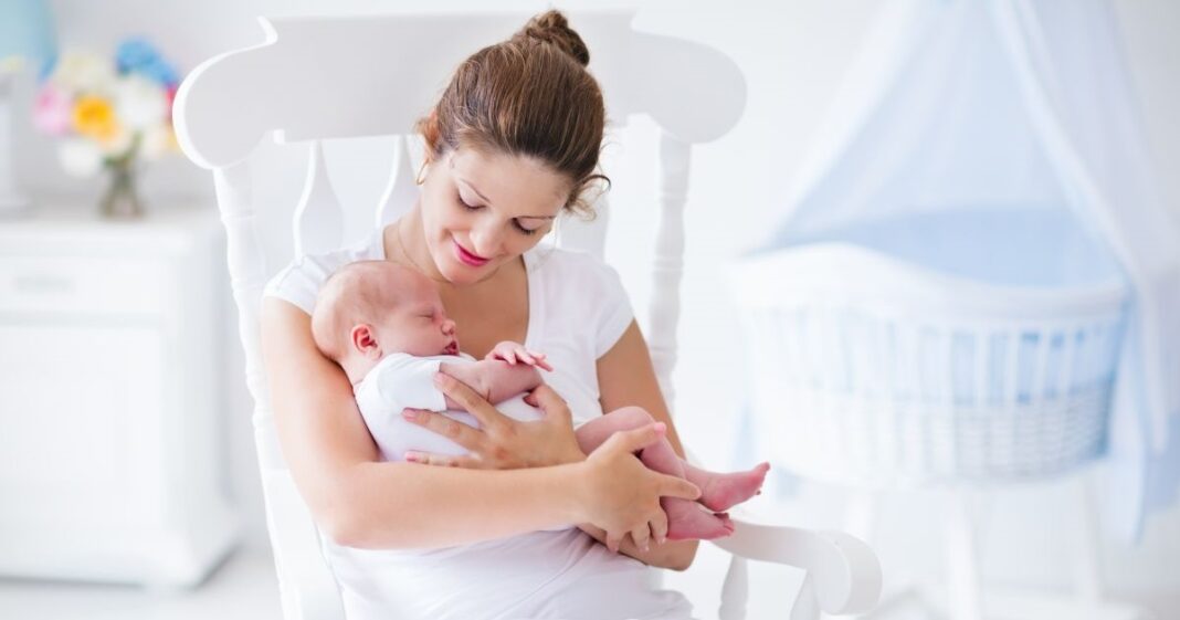 Egy anyuka tart karjaiban egy kisbabát