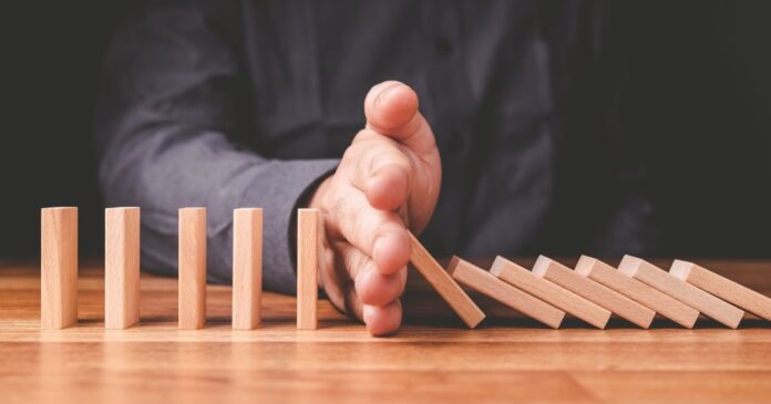Closeup,Businessman,Stop,The,Crash,Of,Domino,Effect,On,The