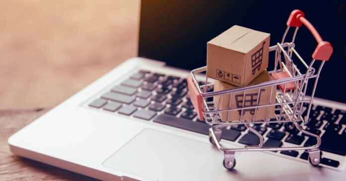 egy laptop billentyűzeten egy mini bevásárlókocsi tele dobozokkal