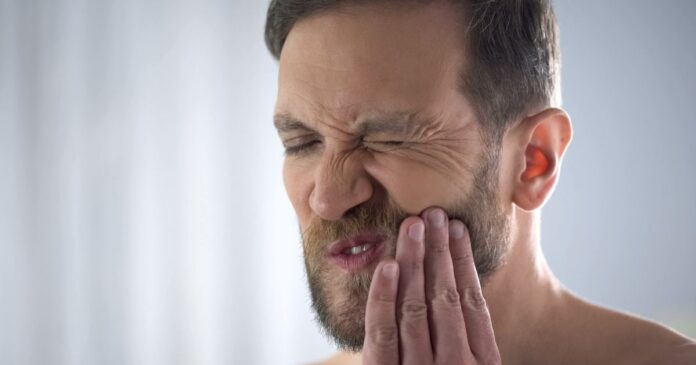 Középkorú férfi fogja az arcát fogfájás miatt
