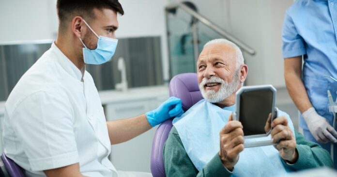 Kedvesen mosolygó idős úr a fogáaszaton a fogorvossal