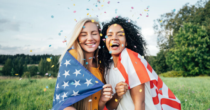 USA vízum igénylés Két lány, konfettivel, boldogan, amerikai zászlót ölelve mosolyog