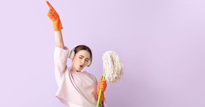 Felmosóval táncoló és zenét hallgató nő