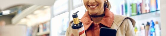 egy nő egy drogériában sampont néz vidáman