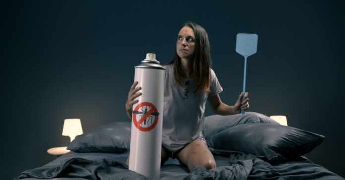 Egy nő légycsapóval és sprayvel az ágyban