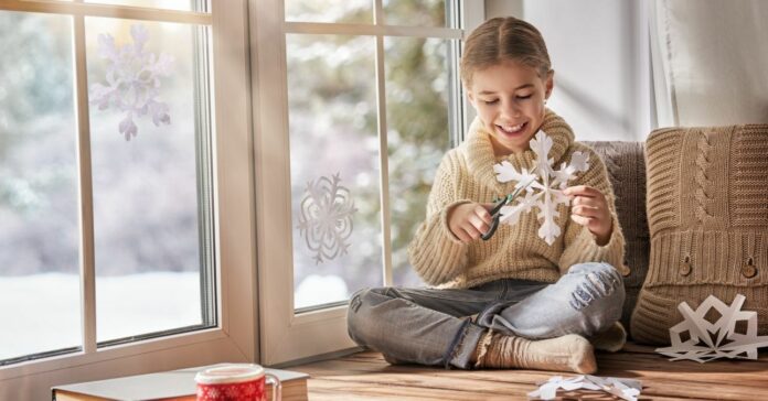 Cute,Little,Girl,Sitting,By,The,Window,And,Looking,At Ünnepi hangulat fillérekből: karácsonyi ablakdekoráció házilag