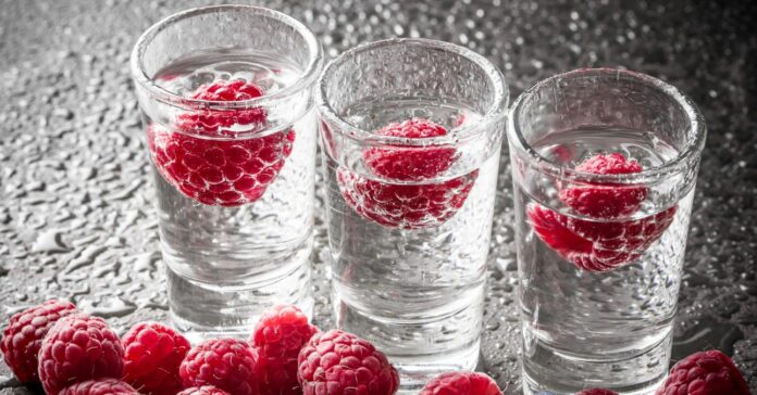 három áttetsző feles pohár vodkával, málnával