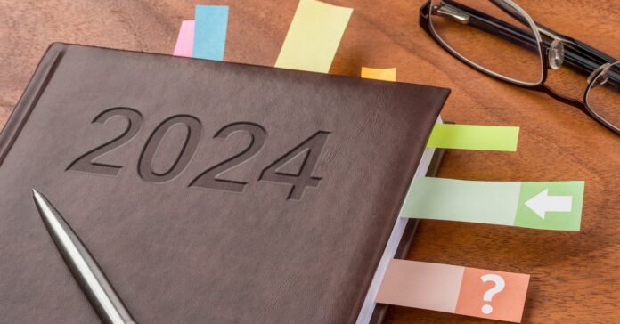 2024-es határidőnapló színes könyvjelzőkkel, tollal és szemüveggel