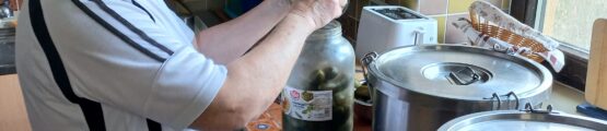 Nő konyhában savanyúságot készít, nagy üveget tartva