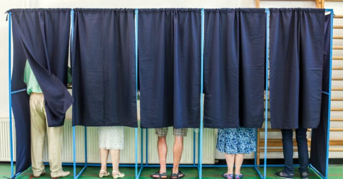 szavazófülkék egymás mellett, elhúzott függönnyel, mindegyikben egy-egy választó