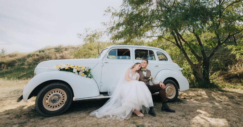 mennyasszony és vőlegény old-school autó előtt pózol