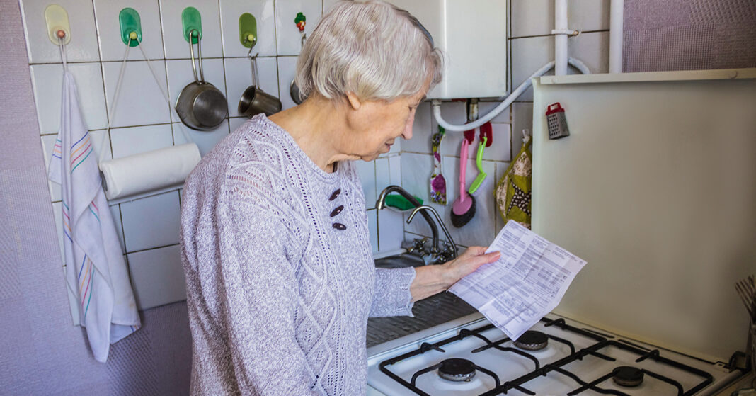 idős hölgy nézi a gázszámlát a gáztűzhelynél