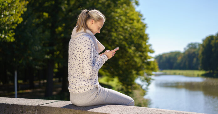 telefonozó nő a folyóparton