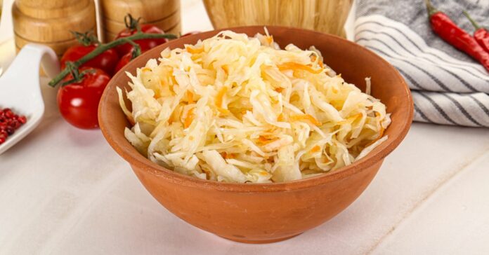 Házi erjesztett káposzta télire, sárgarépával. Savanyú káposzta egy nagy barna tálban, a háttérben fűszertartók