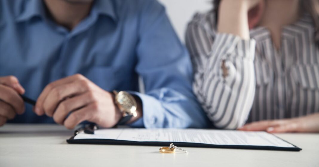 Pár válási szerződéssel és gyűrűvel az asztalon.