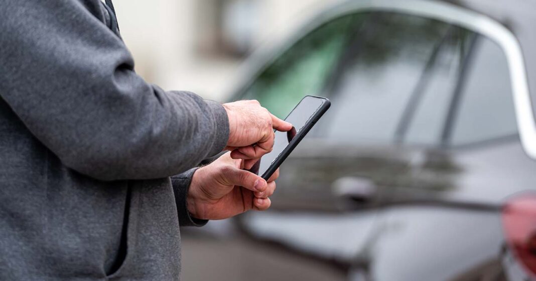 Egy férfi a telefonján küldi a parkoló sms üzenetet a mobilparkolás rendszerben