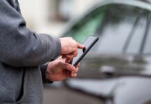 Egy férfi a telefonján küldi a parkoló sms üzenetet a mobilparkolás rendszerben