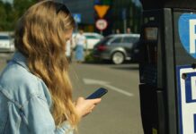 Mobilparkolás: fiatal nő éppen parkoló sms üzenetet küld a telefonjáról
