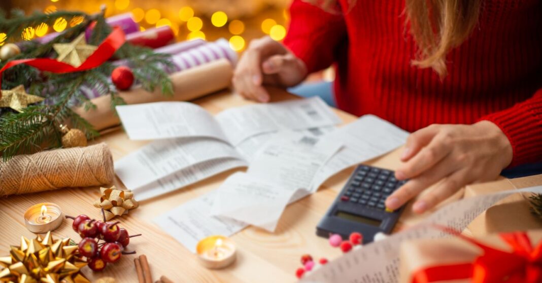 családon belüli ajándékozás karácsonyi díszek között a költségeket számolja egy nő a számlákat összevetve