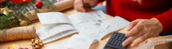 karácsonyi díszek között a költségeket számolja egy nő a számlákat összevetve