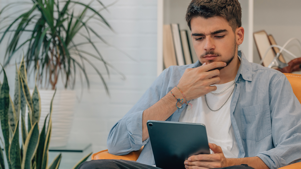 táblagépet néz és gondolkozik a férfi