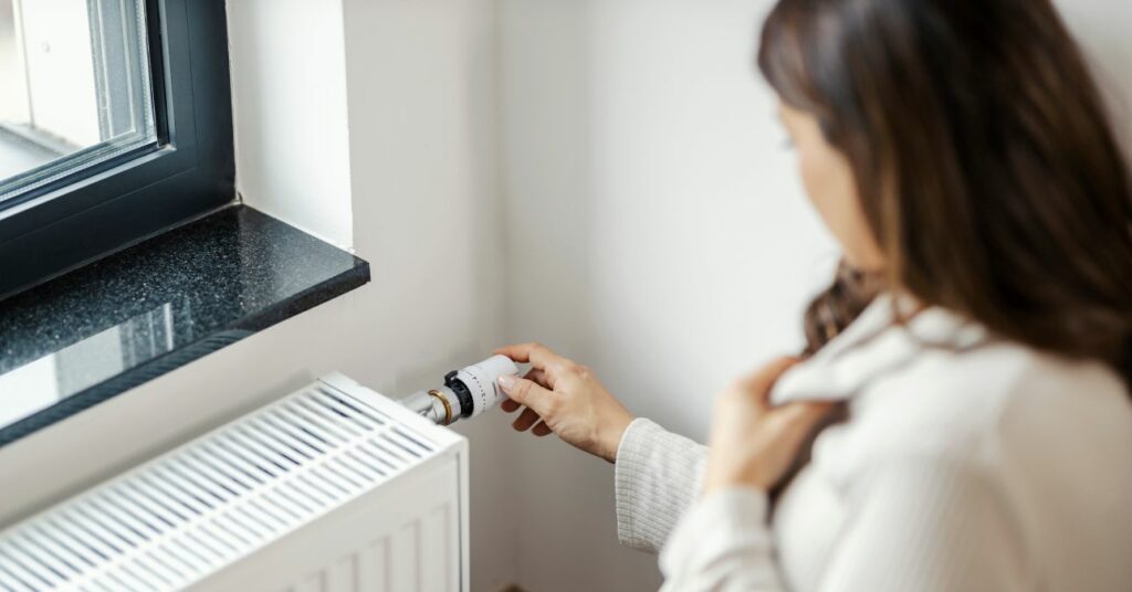 terhes nő feltekeri a radiátort az otthonában