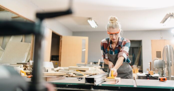 jól fizető szakmák érettségi nélkül profi asztalos munka közben, szőke nő kockás ingben asztalosműhelyben dolgozik