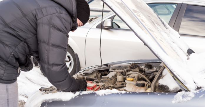 elromlott autót vizsgál a sofőr téli kabátban