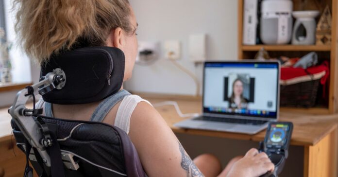 kerekesszékes nő szemben a laptopjával munkamegbeszélésen vesz részt online