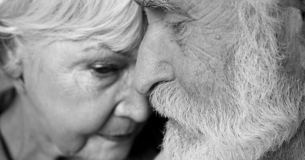 fekete-fehér fotó, idős. nyugdíjas pár, arcuk finoman összeér
