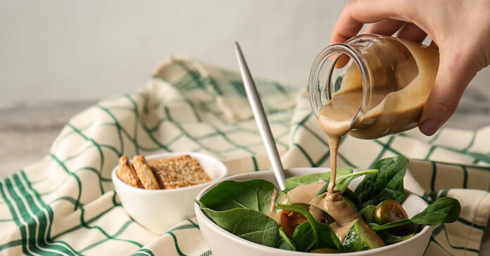 Tahini-szója szószt önt egy férfikéz a salátájára
