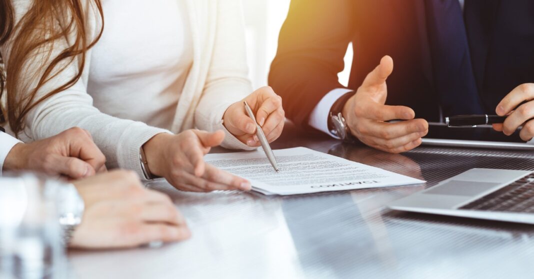 nő kezében tollat és papírt tart egy asztalnál