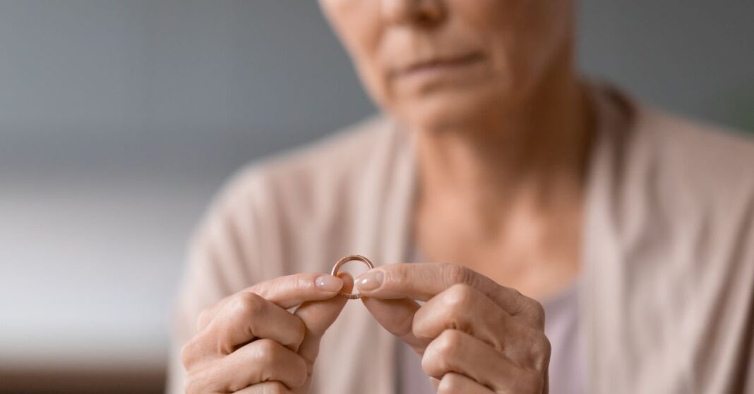idősebb nő szomorúan fogja a karikagyűrűjét elhunyt férjét hiányolva, az arca csak félig látszik