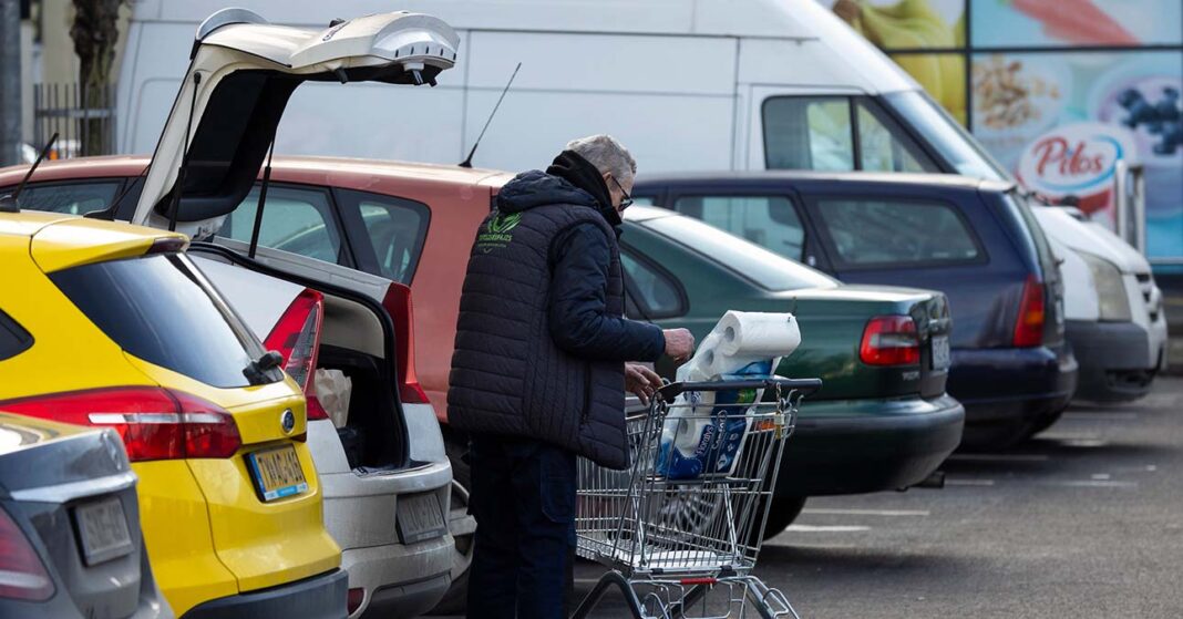 idős férfi bevásárlókocsival egy áruház parkolójában