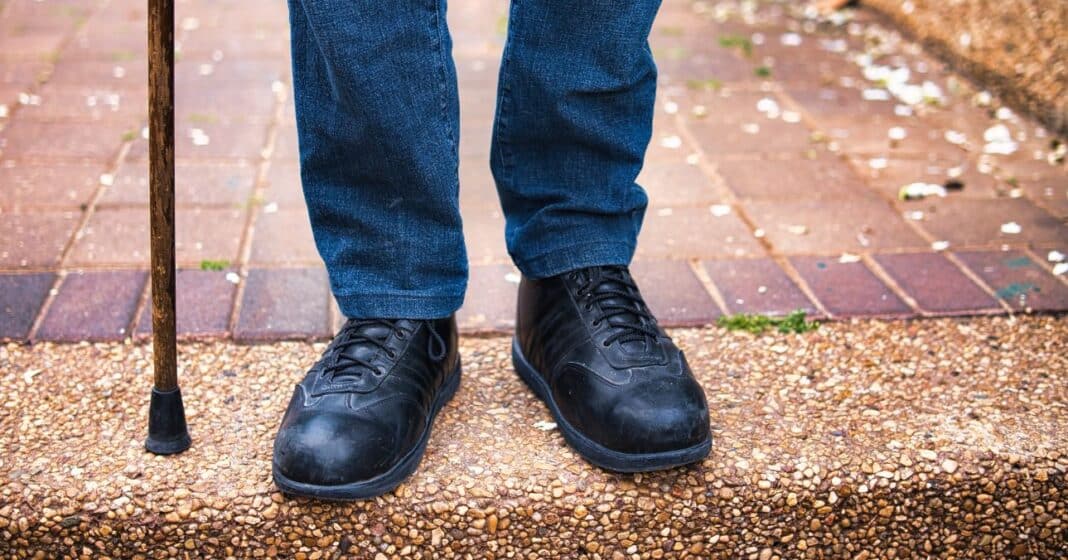 férfi lába térdtől lefelé, botra támaszkodik