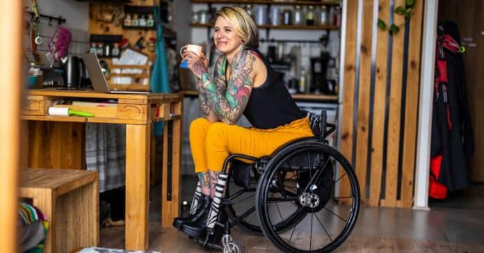 fiatal, szőke lány kerekesszékben egy bögrével