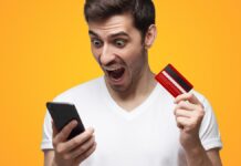 Dühös és meglepett férfi fogja egyik kezében a kártyáját, másikban a telefonját