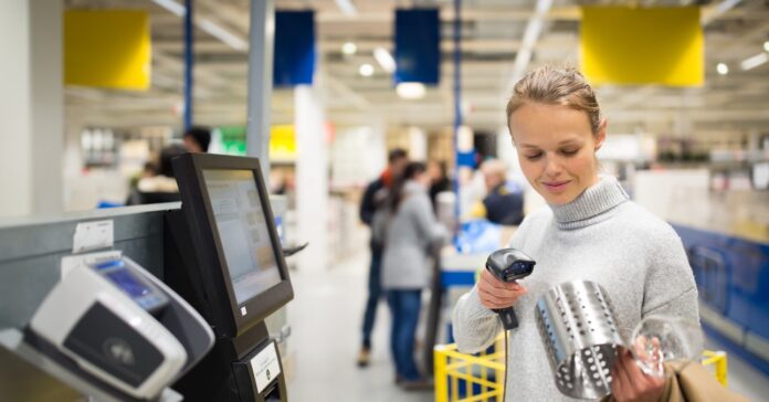 nő vásárol az önkiszolgáló kasszánál az IKEA áruházban