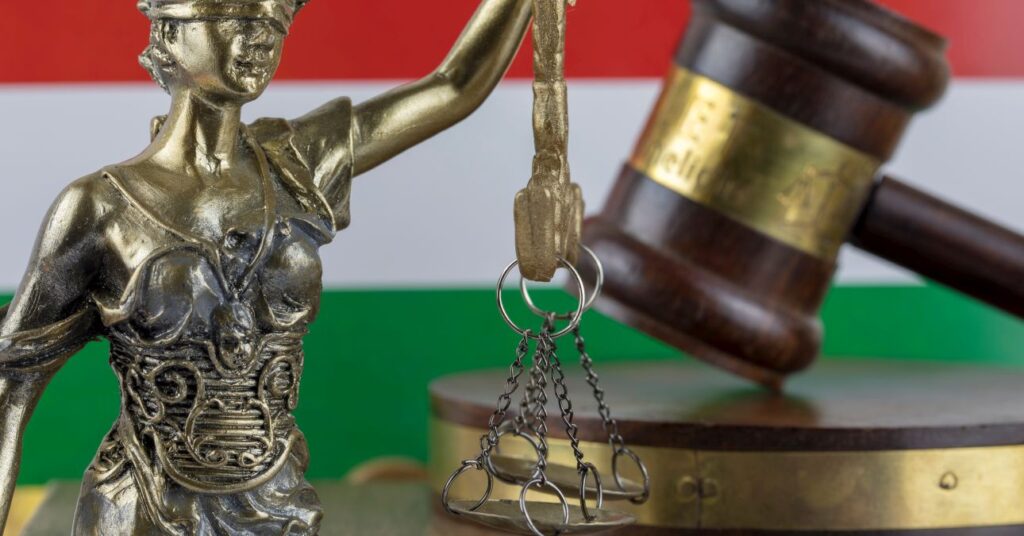 magyar zászló előtt bírói kalapács és mérleget tartó Justicia szobor