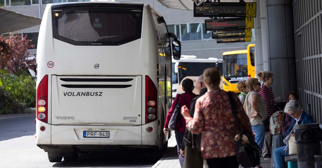 Fehér volánbusz az állomáson, felszálló utasok
