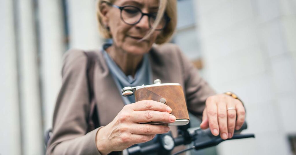 Idős hölgy alkoholproblémával: laposüveg a kézben