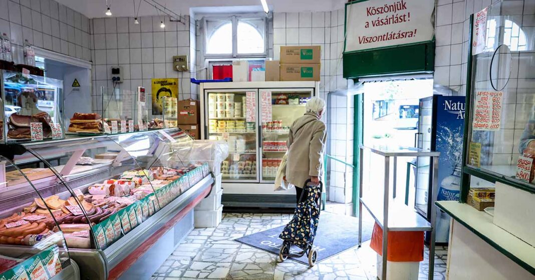 nyugdíjas nő gurulós bevásárlókocsit húzva távozik a hentestől