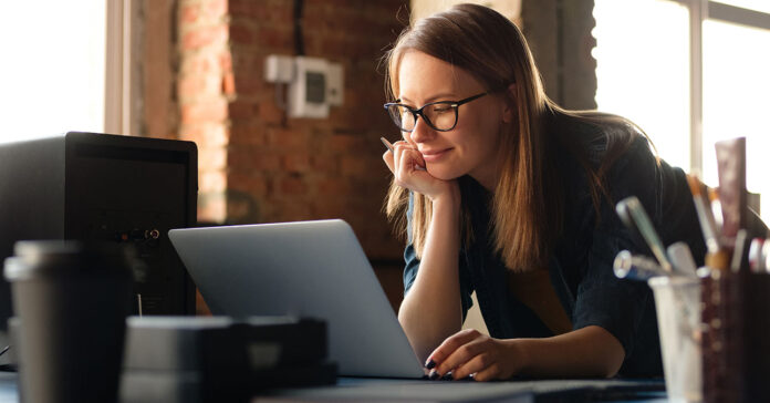 Fiatal, csinos nő Windows rendszerű számítógépet használ