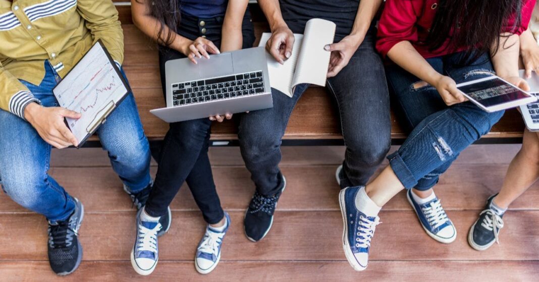 fiatalok egymást mellett, egyik ülében egy laptop