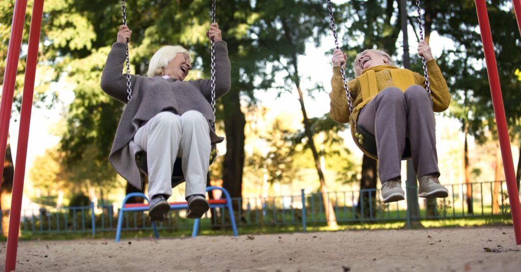 2 nyugdíjas barátnő a parkban hintázik