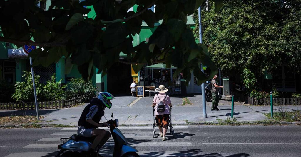 nyugdíjas átsétál a zebrán, egy robogós hajt át mögötte